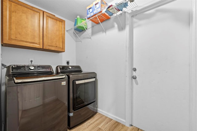 laundry area featuring cabinets, a textured ceiling, light hardwood / wood-style floors, and washing machine and clothes dryer