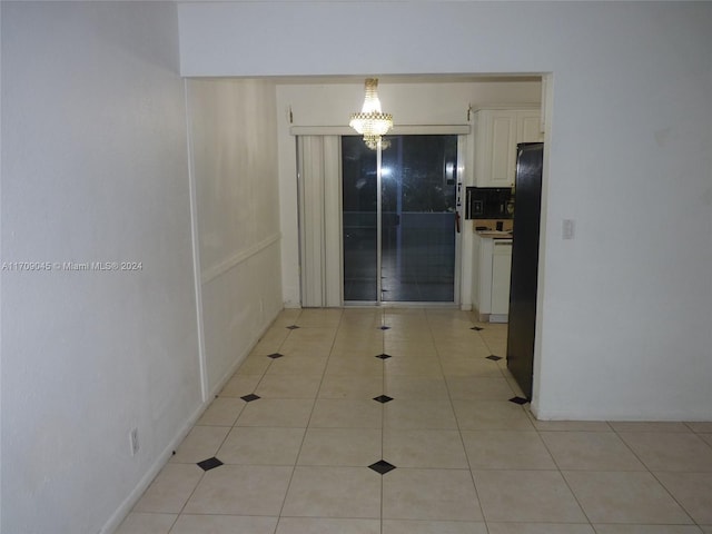 hallway with light tile patterned flooring and a notable chandelier