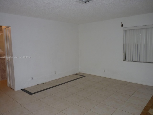 tiled spare room featuring a textured ceiling