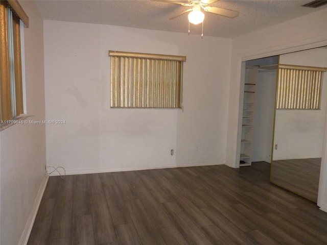 unfurnished bedroom featuring a textured ceiling, dark hardwood / wood-style flooring, a closet, and ceiling fan