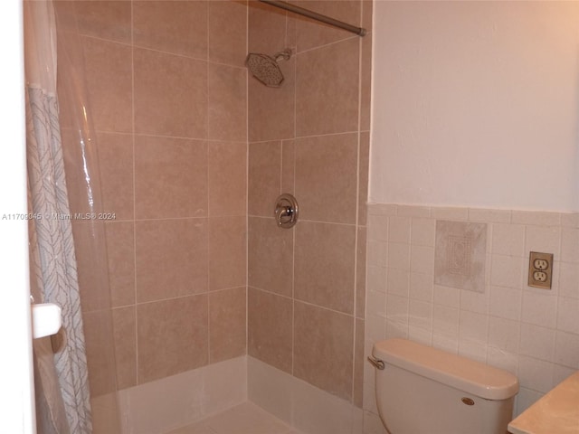 bathroom featuring curtained shower, toilet, and tile walls