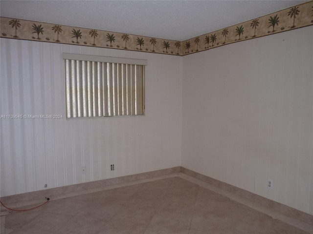 unfurnished room with tile patterned flooring and a textured ceiling