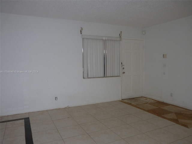 spare room with light tile patterned floors and a textured ceiling