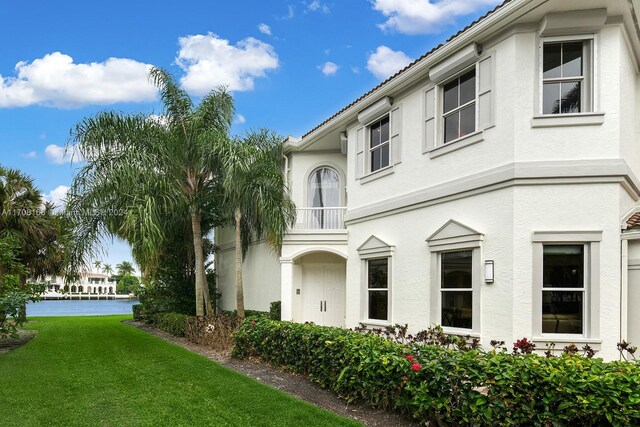 view of side of property with a lawn and a balcony