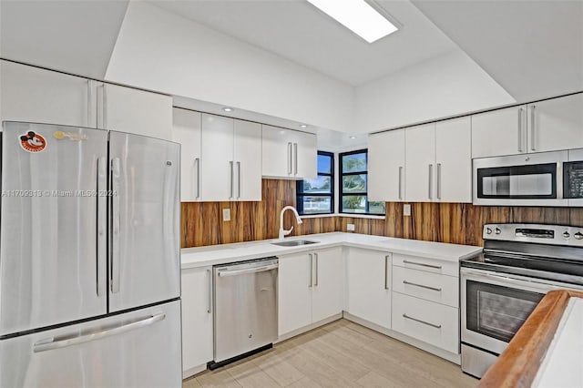 kitchen with light hardwood / wood-style flooring, stainless steel appliances, white cabinetry, and sink