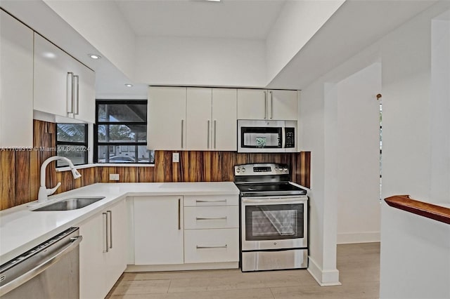 kitchen featuring light wood-type flooring, stainless steel appliances, white cabinetry, and sink