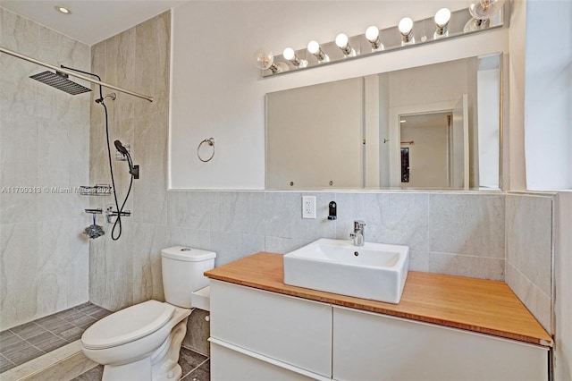 bathroom featuring tiled shower, vanity, toilet, and tile walls