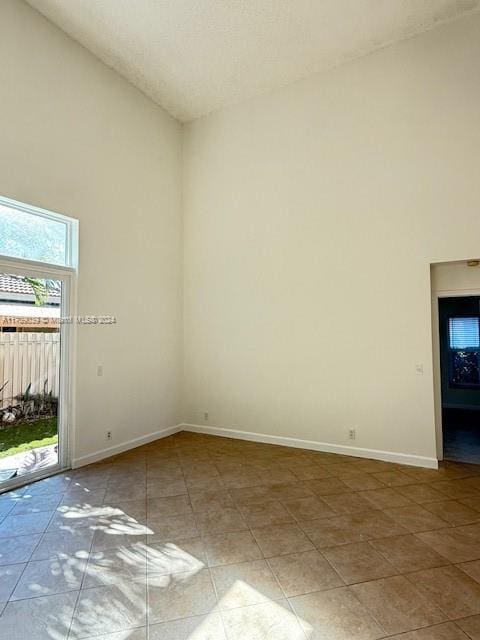 unfurnished room featuring tile patterned floors and a towering ceiling