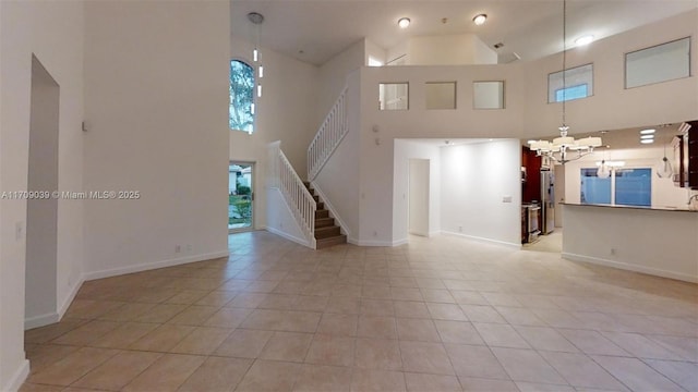 unfurnished living room featuring light tile patterned flooring, a towering ceiling, and a chandelier