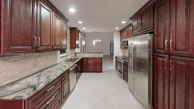 kitchen with tasteful backsplash, appliances with stainless steel finishes, light stone countertops, pendant lighting, and a sink