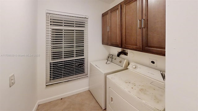 clothes washing area featuring light tile patterned floors, washing machine and dryer, cabinet space, and baseboards