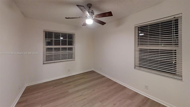 spare room featuring ceiling fan, a textured ceiling, baseboards, and light wood-style floors