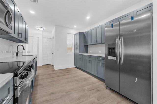 kitchen with stainless steel appliances, light hardwood / wood-style flooring, tasteful backsplash, and sink