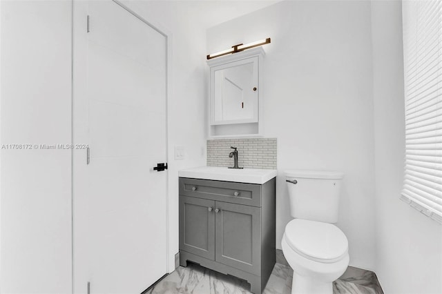 bathroom featuring vanity, tasteful backsplash, and toilet