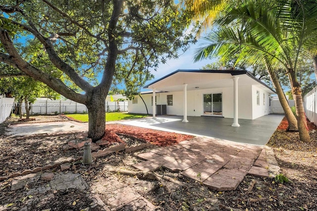 rear view of property with central air condition unit and a patio