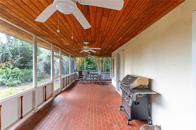 unfurnished sunroom with wooden ceiling, a healthy amount of sunlight, and ceiling fan