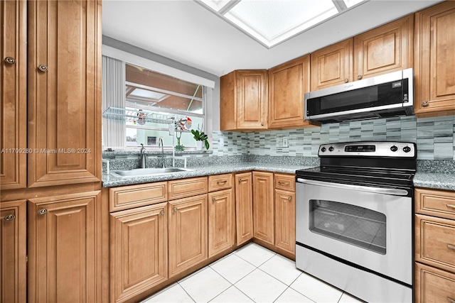 kitchen featuring appliances with stainless steel finishes, backsplash, light tile patterned floors, and sink