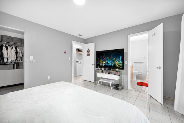 bedroom featuring ensuite bath, a walk in closet, a closet, and light tile patterned floors