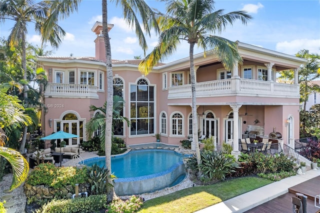 rear view of property featuring ceiling fan, a balcony, an outdoor living space, and a patio