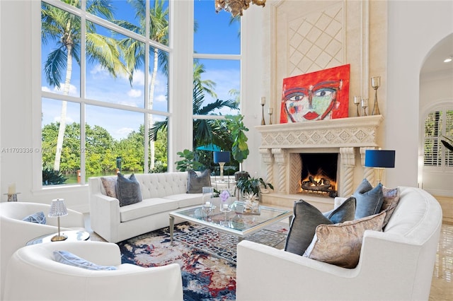 living room with an inviting chandelier, a towering ceiling, and a high end fireplace