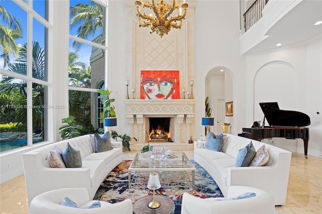 living room with a high ceiling, a chandelier, and a fireplace