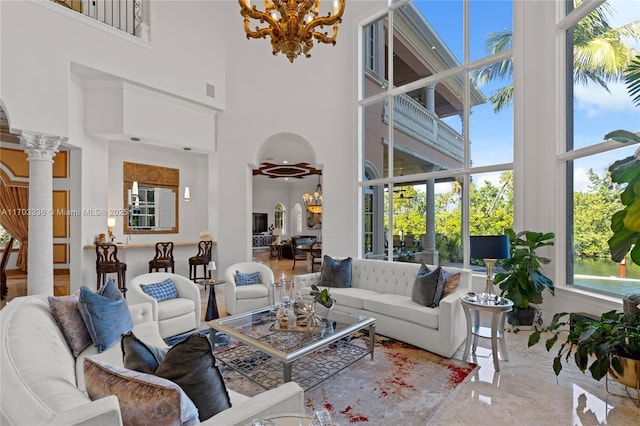 living room with ornate columns, a high ceiling, and an inviting chandelier