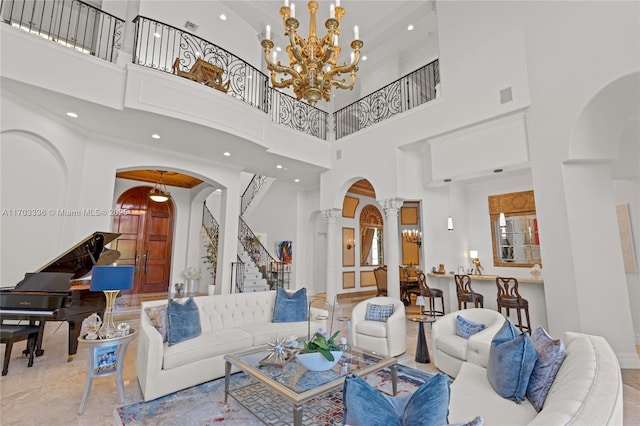 living room with an inviting chandelier, a high ceiling, and ornate columns