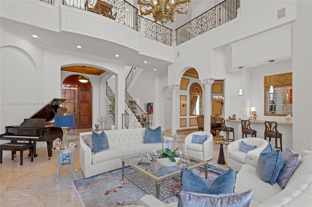 living room featuring ornate columns, crown molding, a towering ceiling, and a notable chandelier