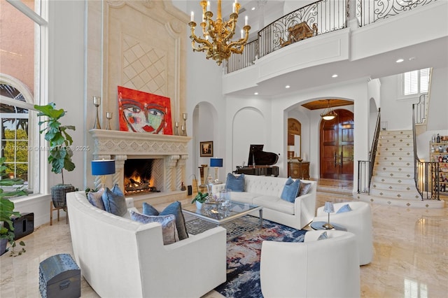 living room with a towering ceiling, a large fireplace, and a chandelier