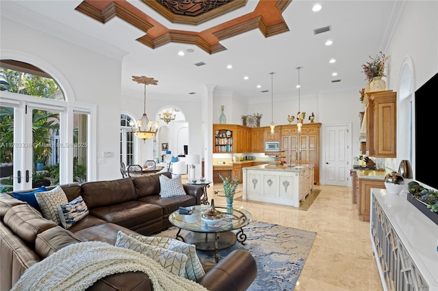 living room with sink, a high ceiling, ornamental molding, an inviting chandelier, and french doors