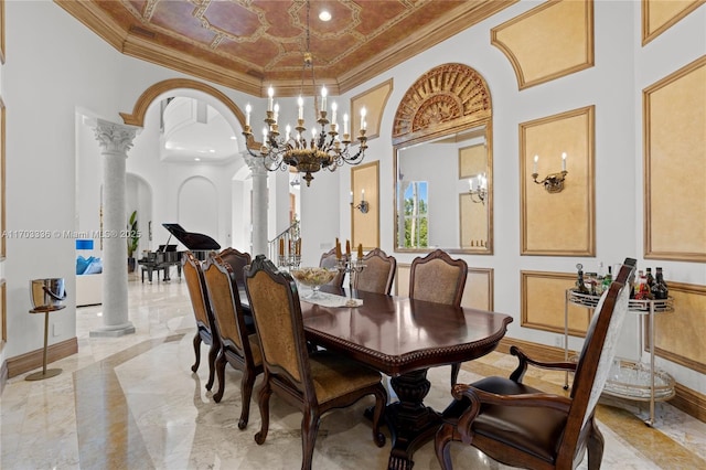 dining space featuring crown molding, a towering ceiling, decorative columns, and a notable chandelier