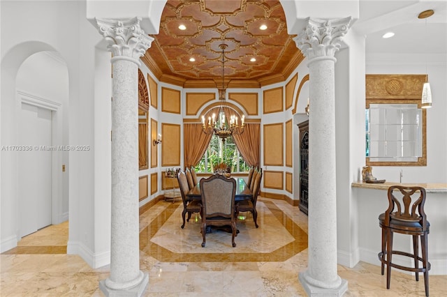 dining space with crown molding, a notable chandelier, and ornate columns