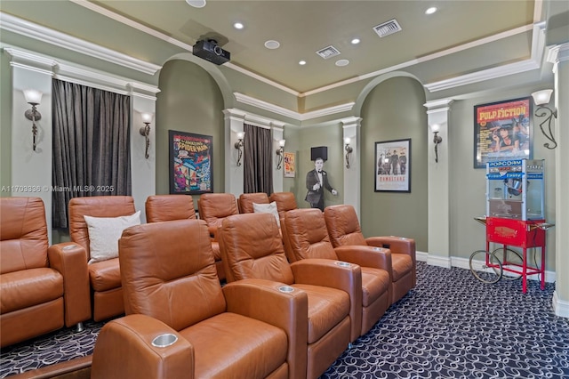 home theater room with ornate columns, dark colored carpet, and crown molding