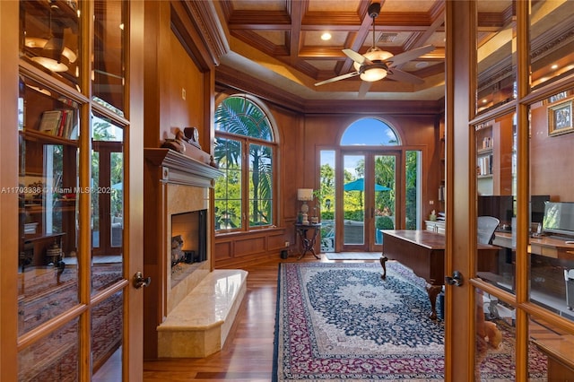 office space featuring a fireplace, hardwood / wood-style flooring, ornamental molding, coffered ceiling, and french doors