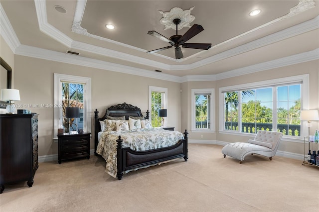 bedroom with crown molding, multiple windows, a tray ceiling, and light carpet