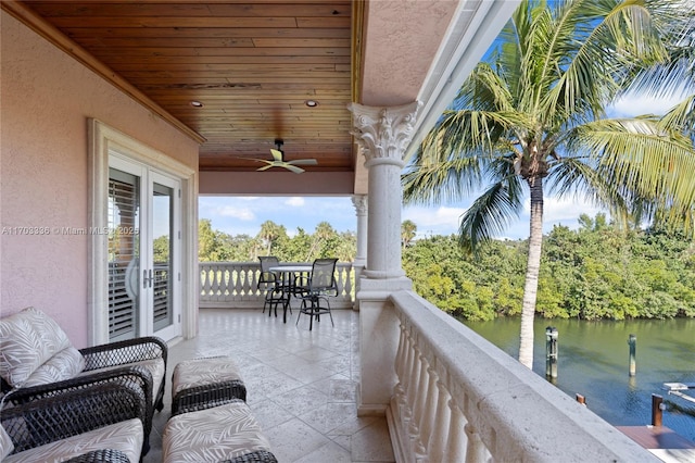 balcony with french doors, ceiling fan, and a water view