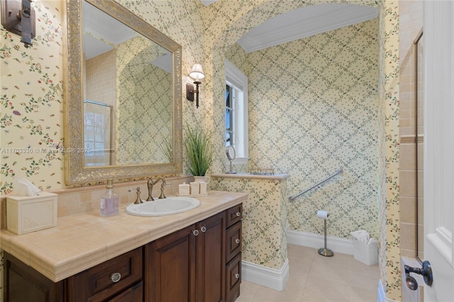 bathroom featuring tile patterned flooring, vanity, crown molding, and walk in shower