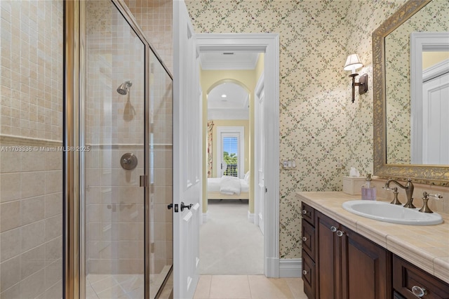 bathroom featuring tile patterned flooring, crown molding, vanity, and a shower with shower door