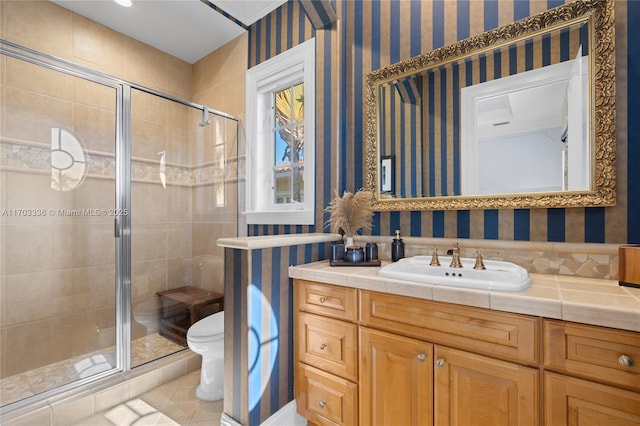 bathroom with a shower with door, vanity, tile patterned floors, and toilet