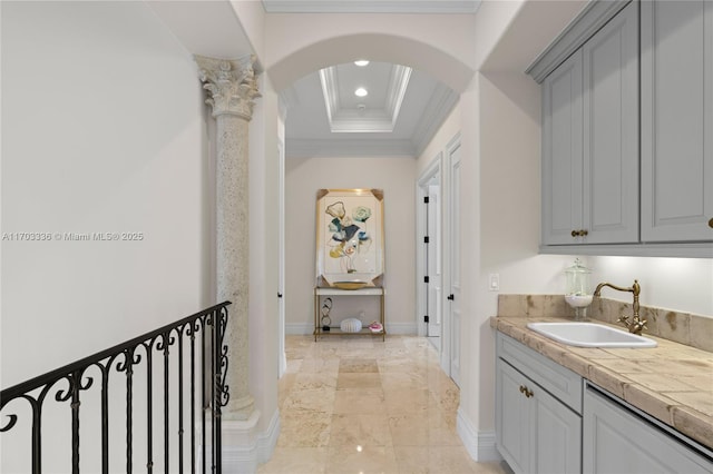 interior space with decorative columns, ornamental molding, sink, and a tray ceiling