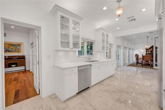 kitchen featuring dishwasher, white cabinetry, sink, and hanging light fixtures