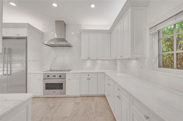 kitchen featuring white cabinets, decorative backsplash, wall chimney exhaust hood, and stainless steel appliances