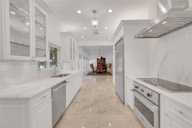 kitchen featuring sink, ventilation hood, decorative light fixtures, white cabinets, and appliances with stainless steel finishes