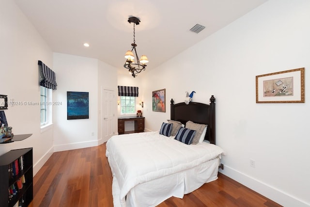 bedroom with a chandelier and dark wood-type flooring