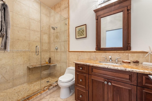 bathroom with vanity, tile walls, tile patterned flooring, toilet, and a shower with shower door