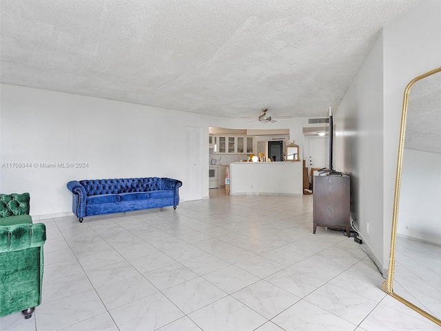 living room featuring ceiling fan and a textured ceiling