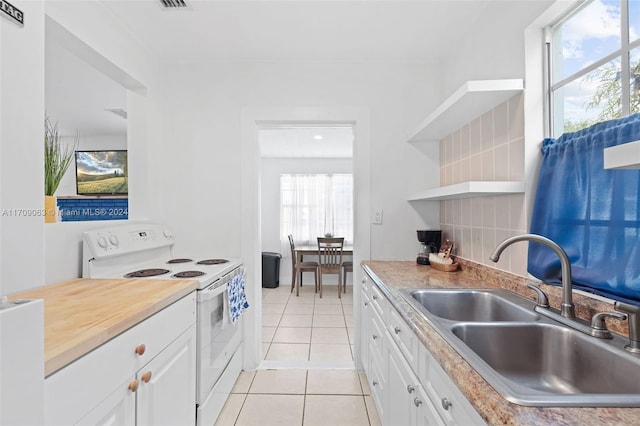 kitchen featuring electric range, white cabinetry, sink, and a wealth of natural light