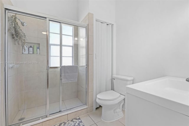 bathroom with toilet, vanity, tile patterned floors, and a shower with shower door