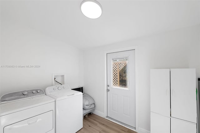 washroom featuring washing machine and clothes dryer, cabinets, and light hardwood / wood-style floors