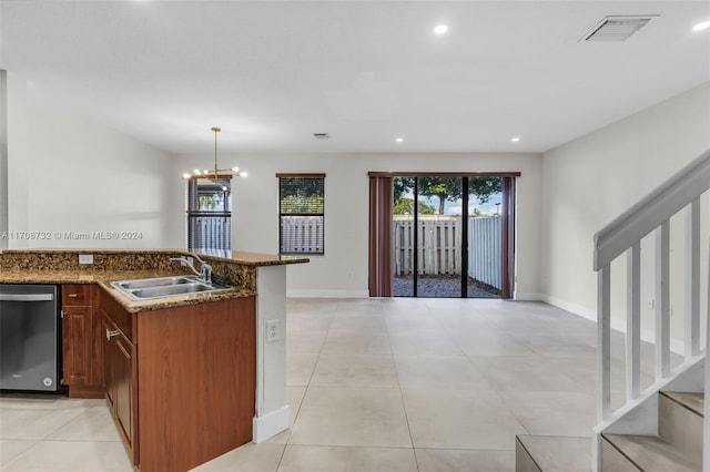 kitchen with stainless steel dishwasher, dark stone counters, sink, decorative light fixtures, and an inviting chandelier